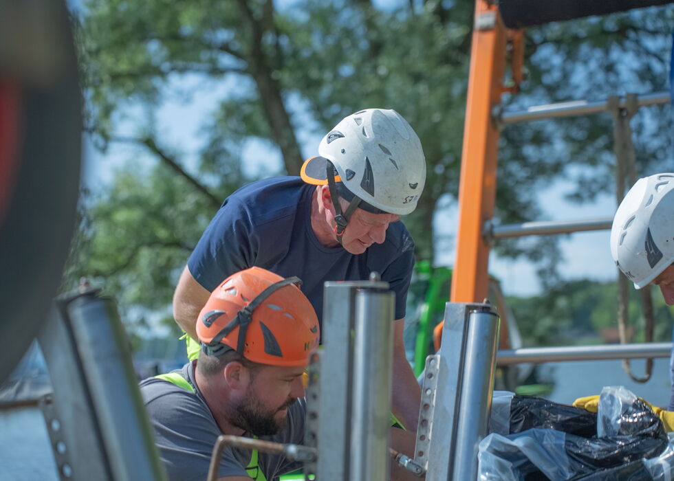 Arbeitende mit Sicherheitshelmen und Handschuhen montieren im Freien Metallträger.