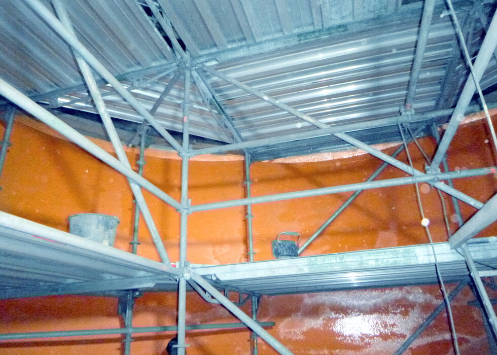 Blick auf ein Metallgerüst in einem Stahlbehälter mit orangefarbenen Wänden.
