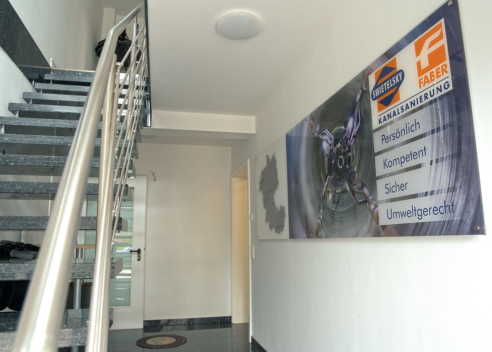 Interior stairwell with metal railings and a large wall banner in a hallway.