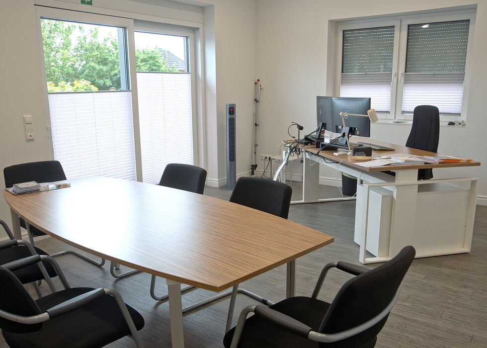 Bright office with a meeting table, desk, chairs, and computer workstation.
