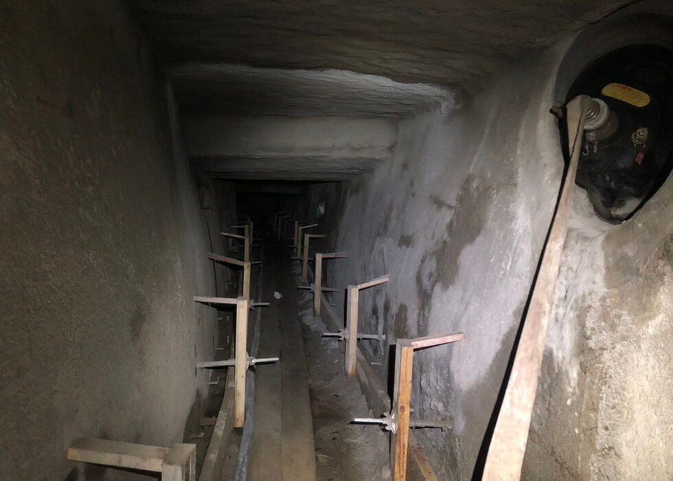 Dunkler unterirdischer Tunnel mit Holzstützen und einem Rohr auf dem Boden