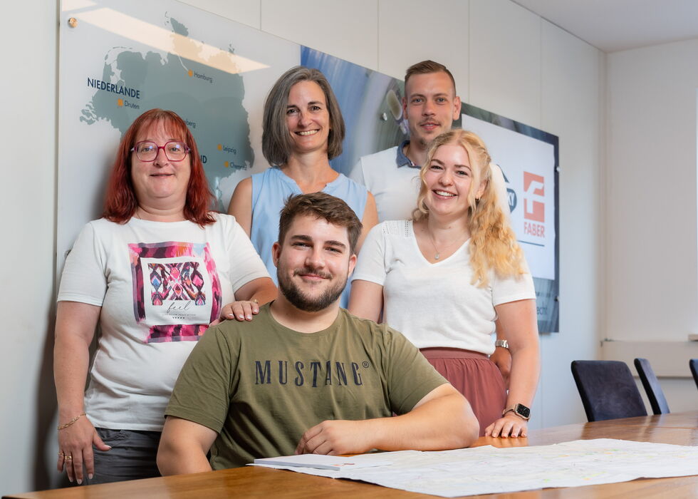 Fünf Kolleginnen und Kollegen posieren gemeinsam in einem hellen Besprechungsraum.