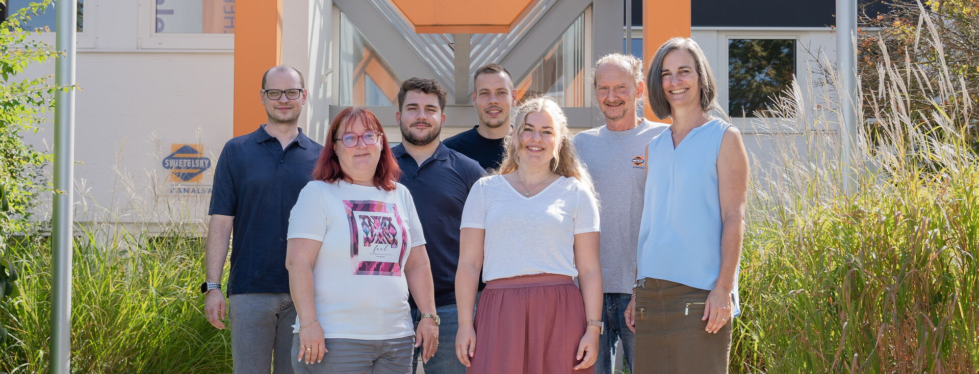 Sechs Kolleginnen und Kollegen stehen gemeinsam im Freien vor einem Bürogebäude.