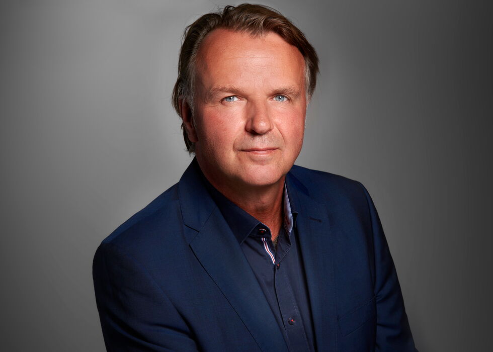 Studio-Porträt Dipl.-Ing. Jörg Brunecker im marineblauen Sakko vor grauem Hintergrund.