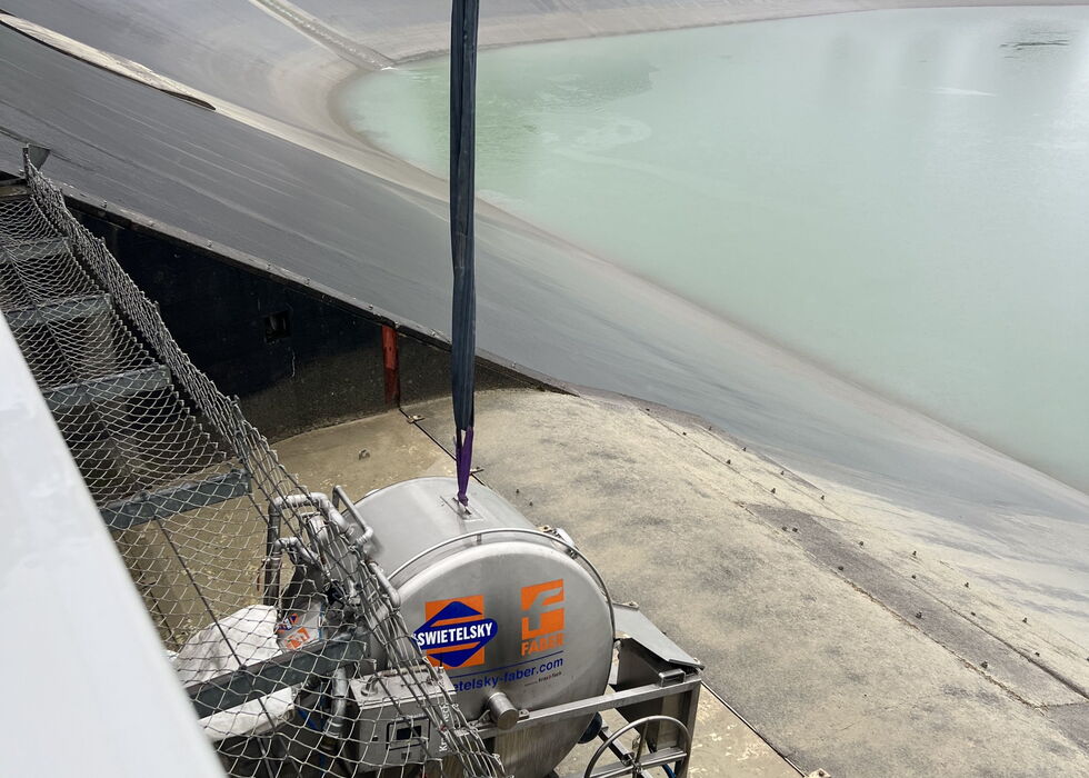 Kran hebt die Liner-Trommel neben einem Stausee.
