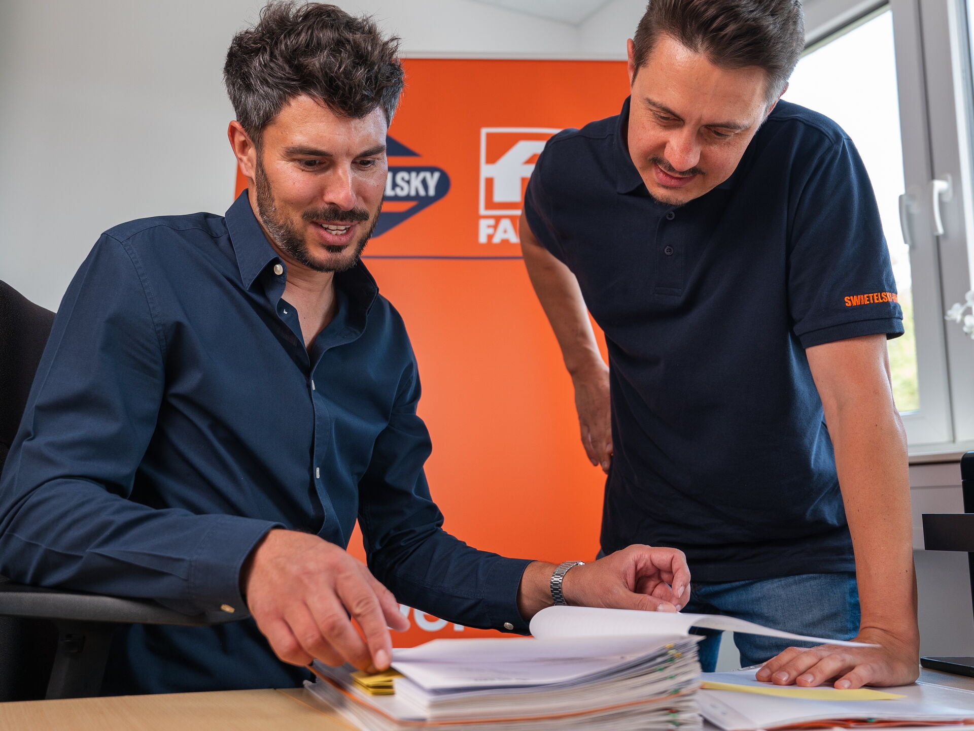 Zwei Männer sehen sich Dokumente an und besprechen sie an einem Bürotisch