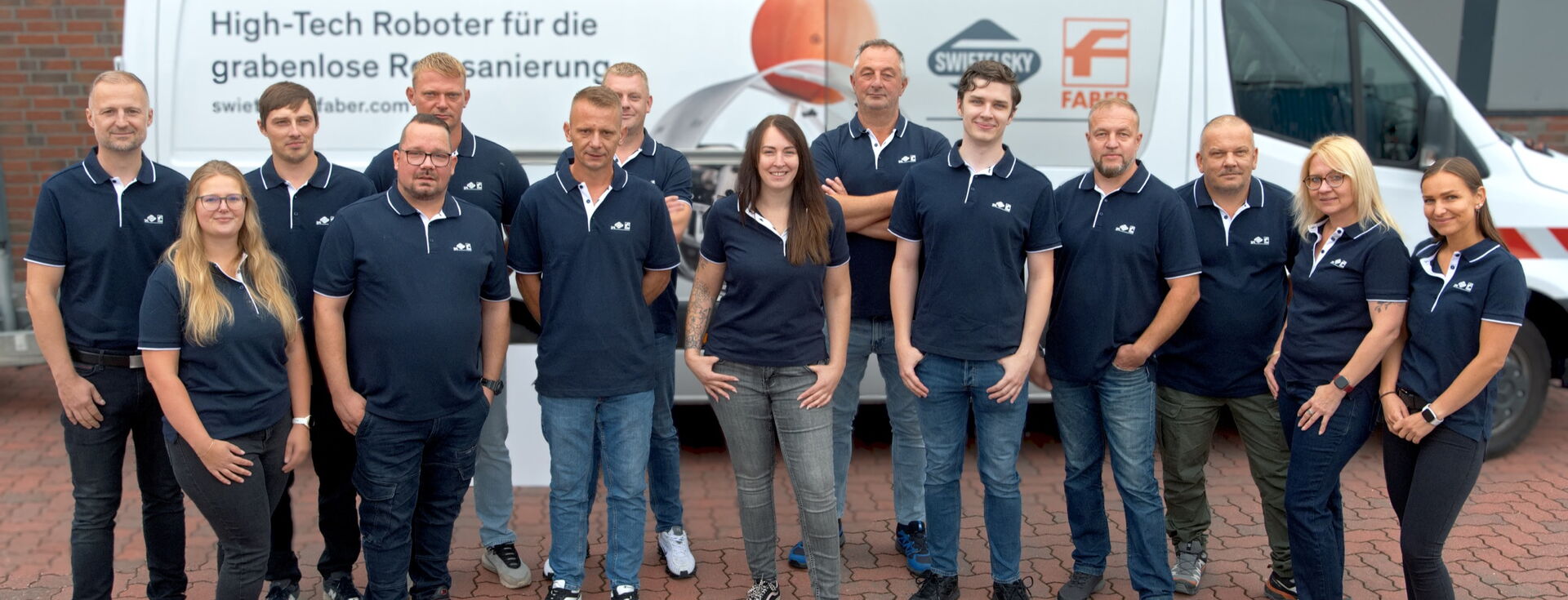 Gruppe von Mitarbeitenden posiert vor einem weißen Servicewagen mit Firmenlogo.