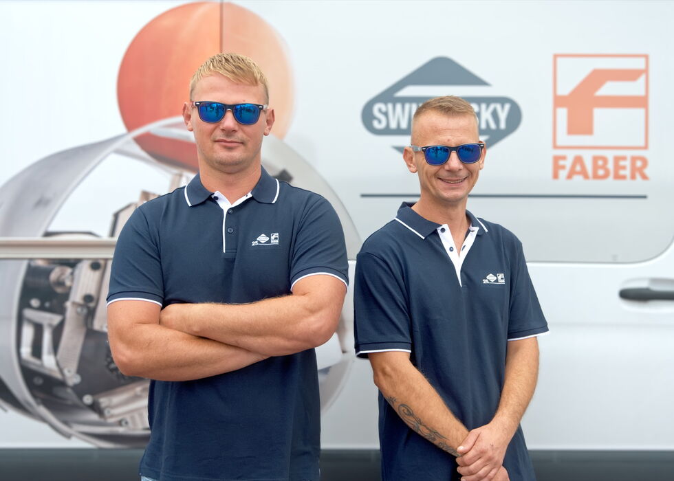 Two men wearing navy polo shirts and sunglasses standing in front of a white branded van.