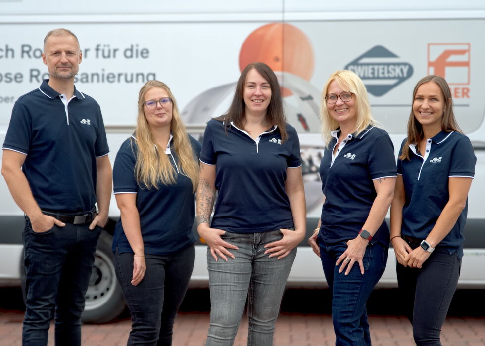 Five employees posing in front of a branded service van.