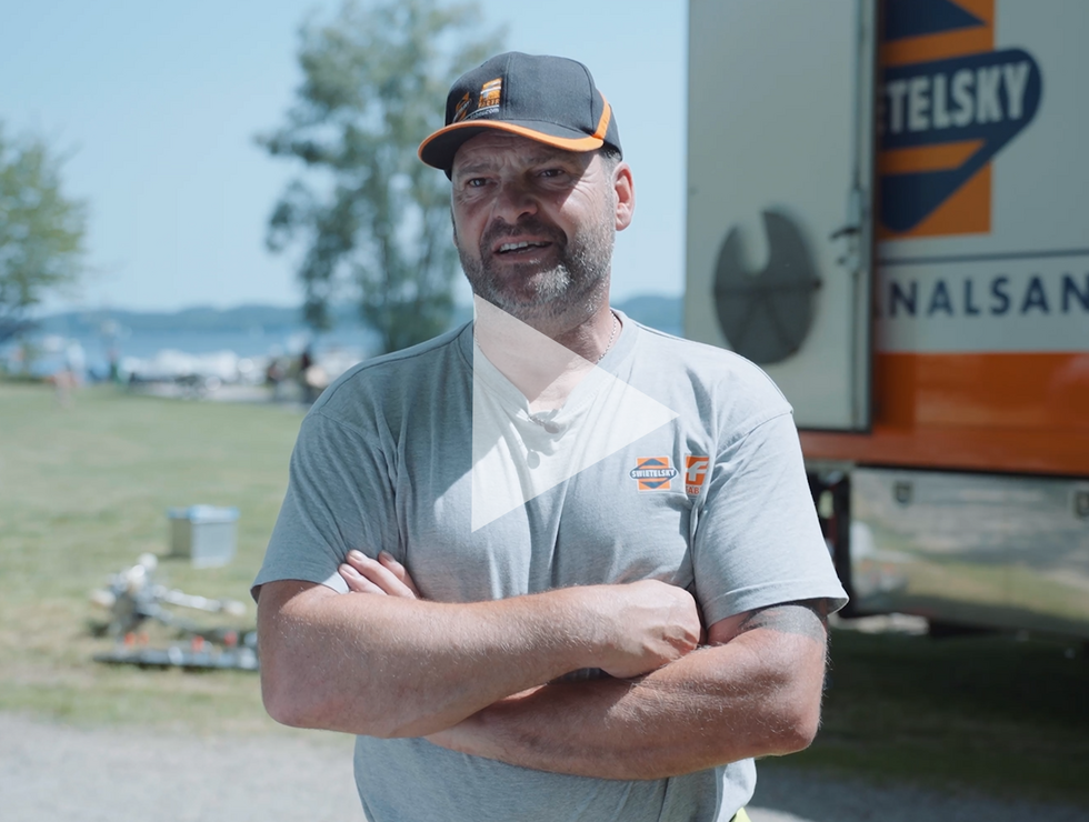 Ein Mann mit Kappe und grauem T-Shirt steht mit verschränkten Armen bei einem TELSKY-Lkw an einem sonnigen Tag