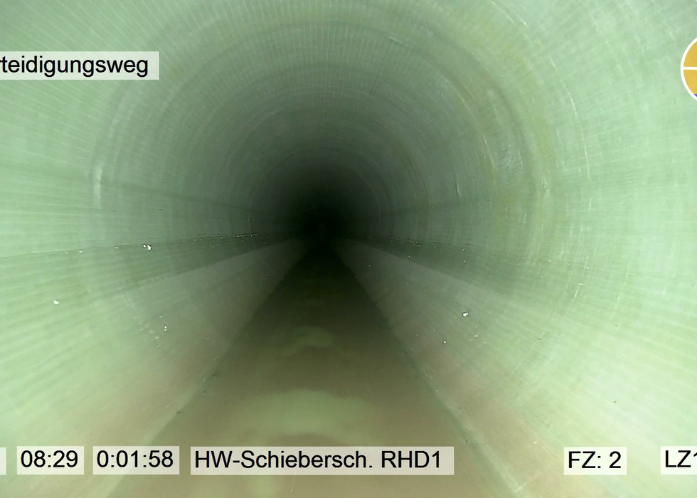 Blick in einen langen grün ausgekleideten Tunnel mit dunklem Zentrum, beschriftet Altrip Deichverteidigungsweg.