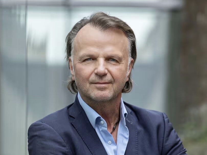 Porträt von Jörg Brunecker mit verschränkten Armen in moderner Außenumgebung.
