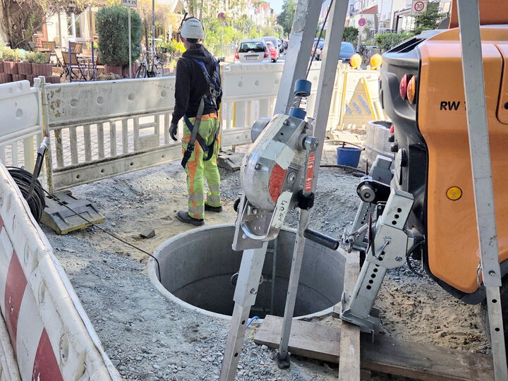 Bauarbeiter an der Straßenbaustelle neben einem offenen Schacht.