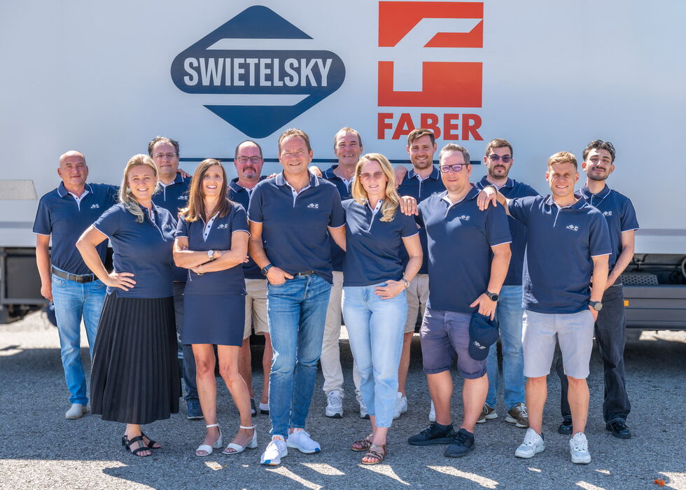 Gruppe von Mitarbeitenden vor einem Lkw mit den Logos von Swietelsky und Faber.