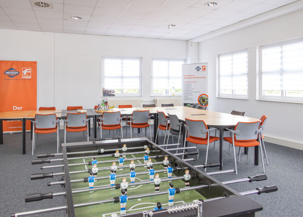 Tischfußballtisch mit Stühlen in einem hellen Büro-Besprechungsraum.