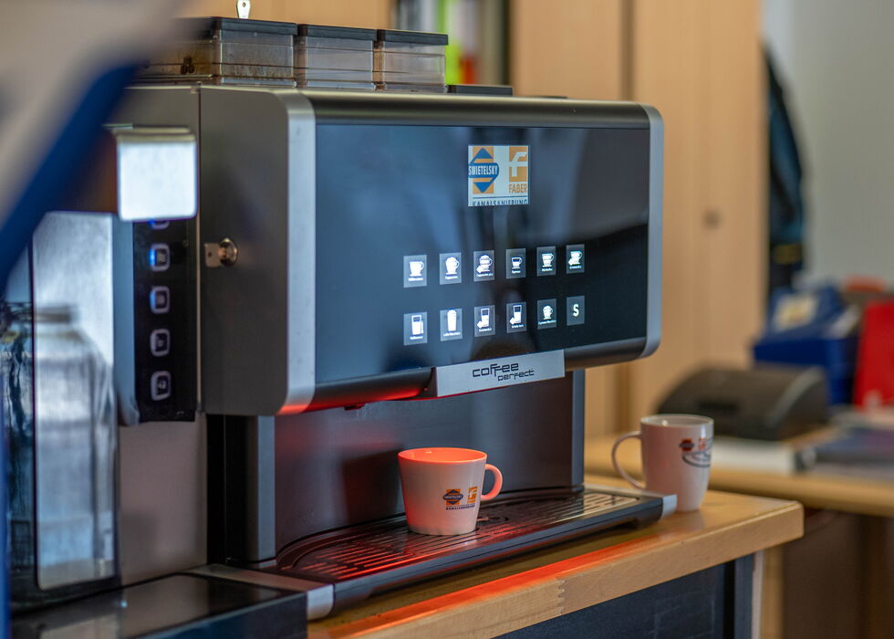 Eine moderne Kaffeemaschine gibt Kaffee in eine Tasse auf der Arbeitsplatte aus.