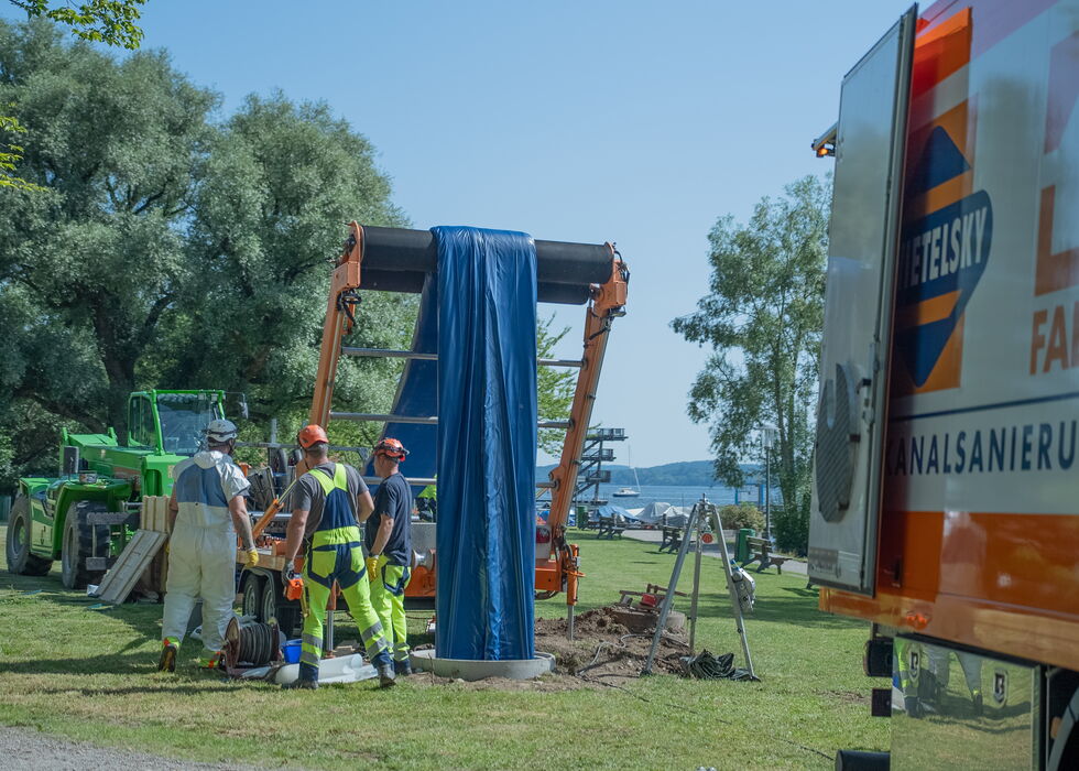 Außenaufnahme: Arbeiter montieren ein blaues Zelt neben einem geparkten Lkw auf einer Wiese.