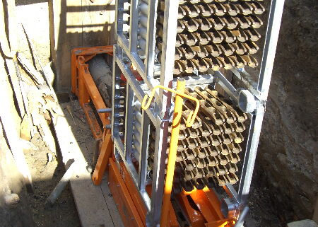 Metallrahmen mit vielen Reihen zylindrischer Bauteile in einer engen Industriegrube.