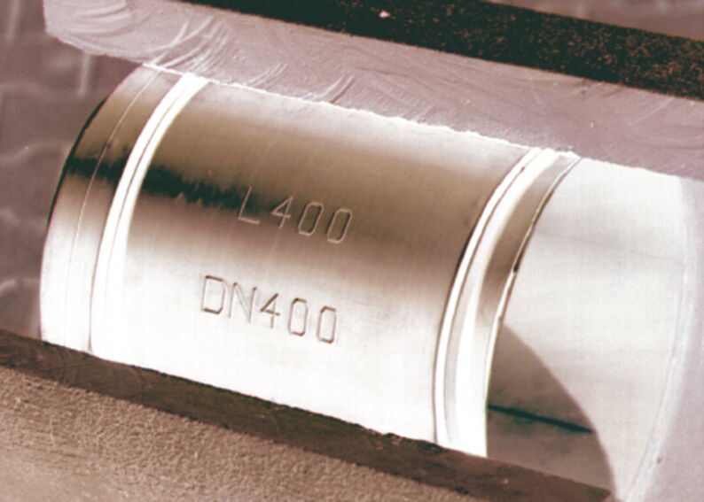 Nahaufnahme einer Stahlrohrverbindung mit der Kennzeichnung L400 DN400 in einer Metallhalterung.